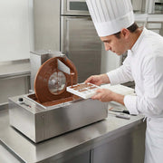 Chef using a chocolate cutting machine in a kitchen setting